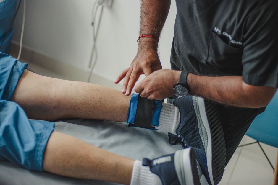 A physiotherapist adjusting a leg strap on a patient